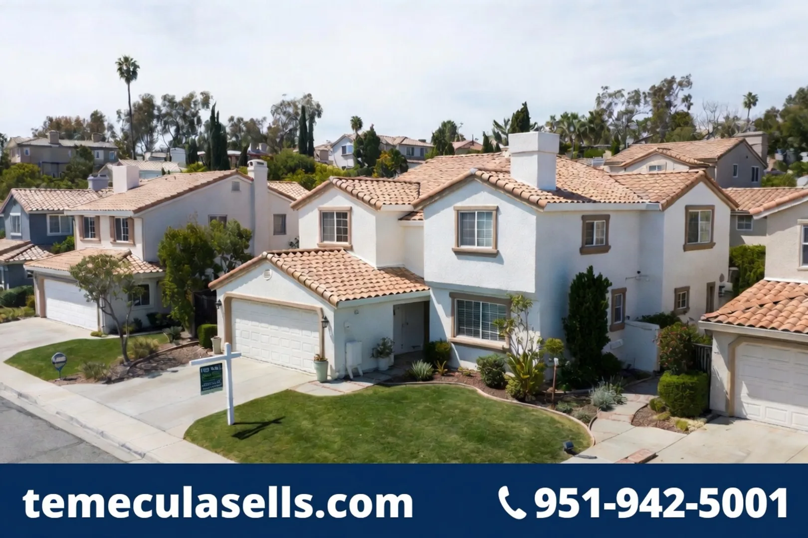 Aerial view of a Temecula neighborhood showing Spanish-tile rooftops, mature trees, and a for-sale sign out front